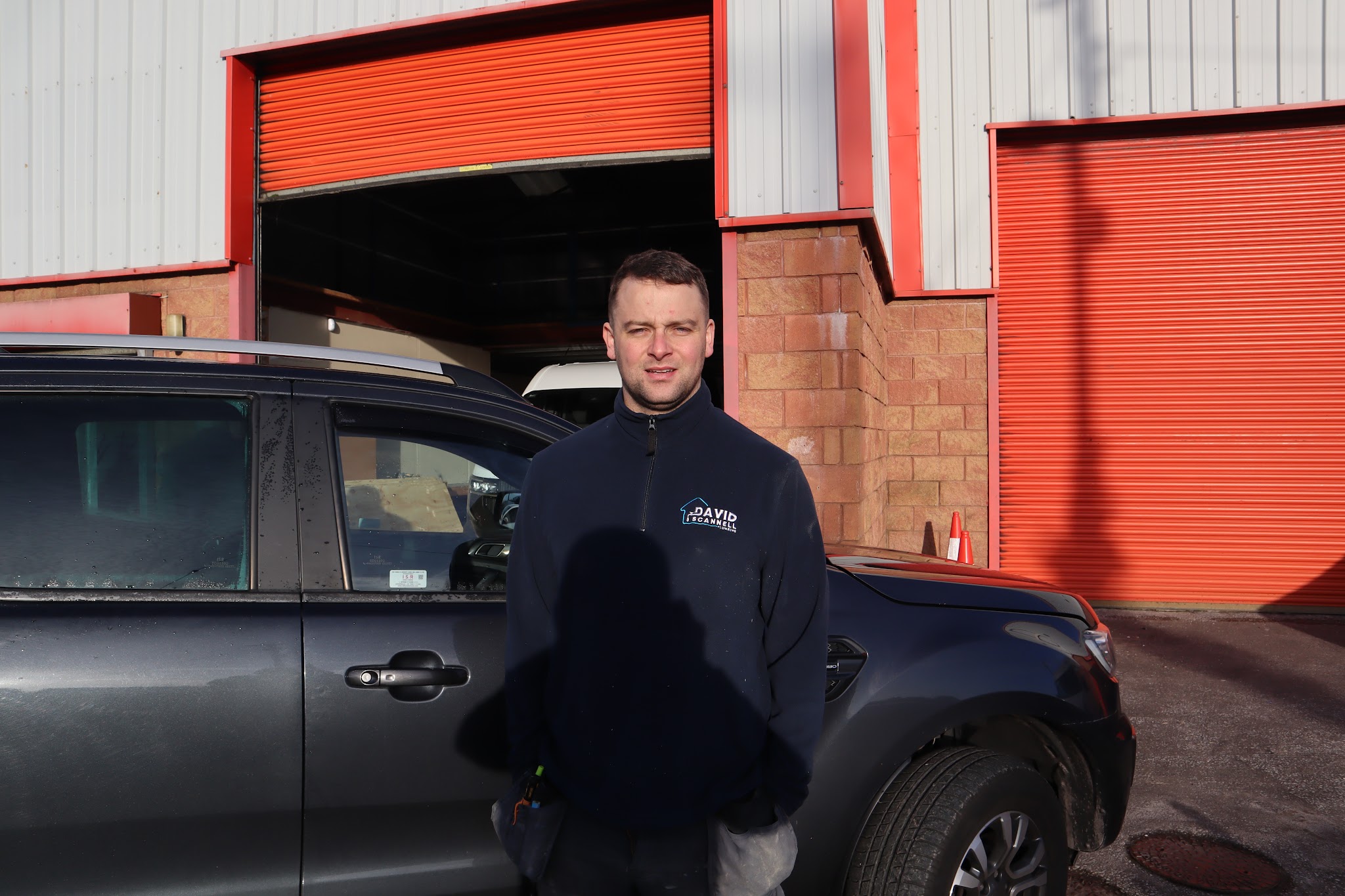 David Scannell standing beside his car outside a unit with an orange roller door