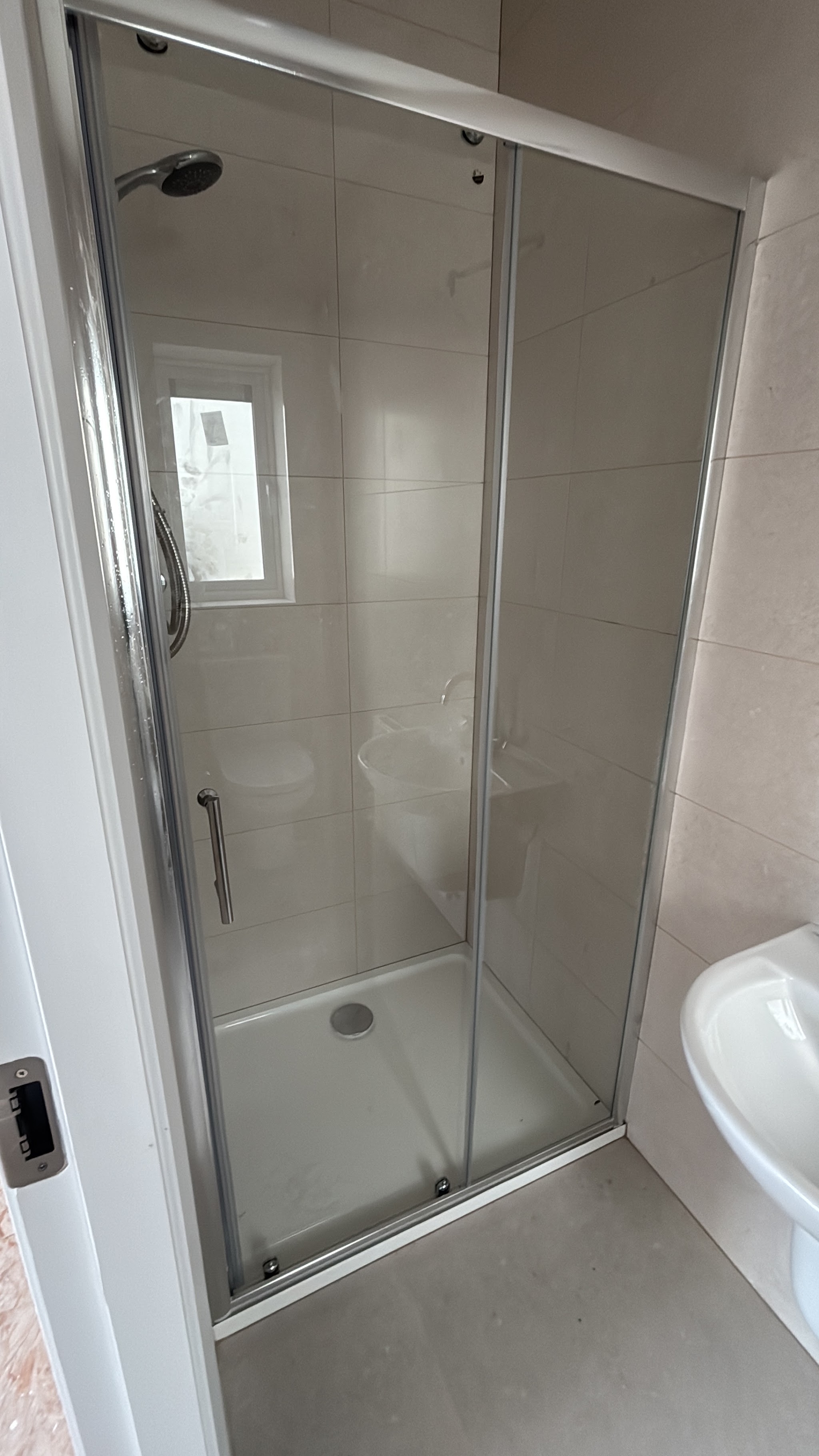 Tall shower enclosure with sliding glass doors and a riser rail shower