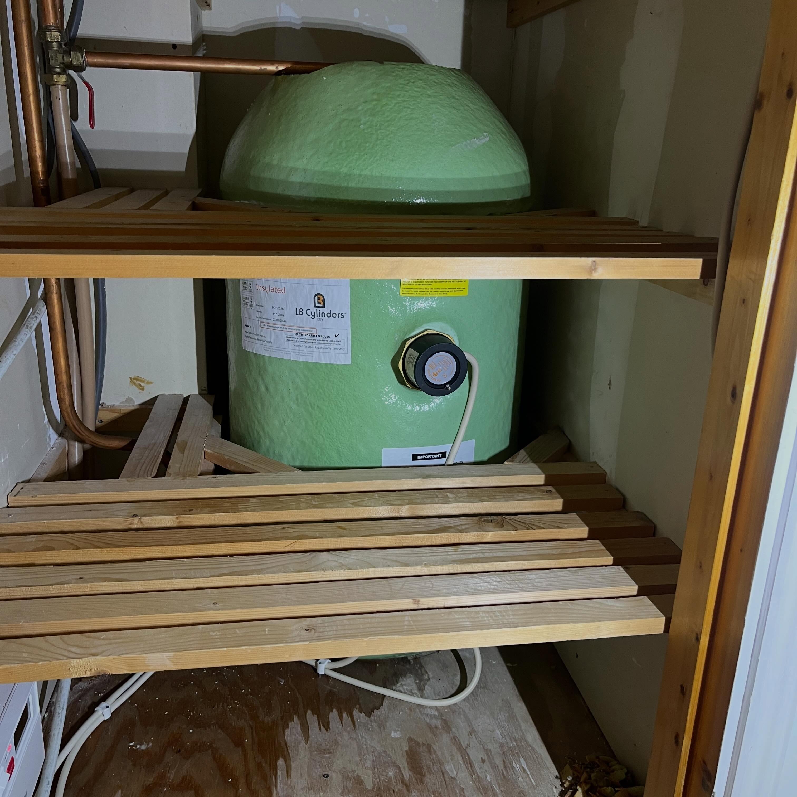 Hot water cylinder in a hot press under slatted timber shelves